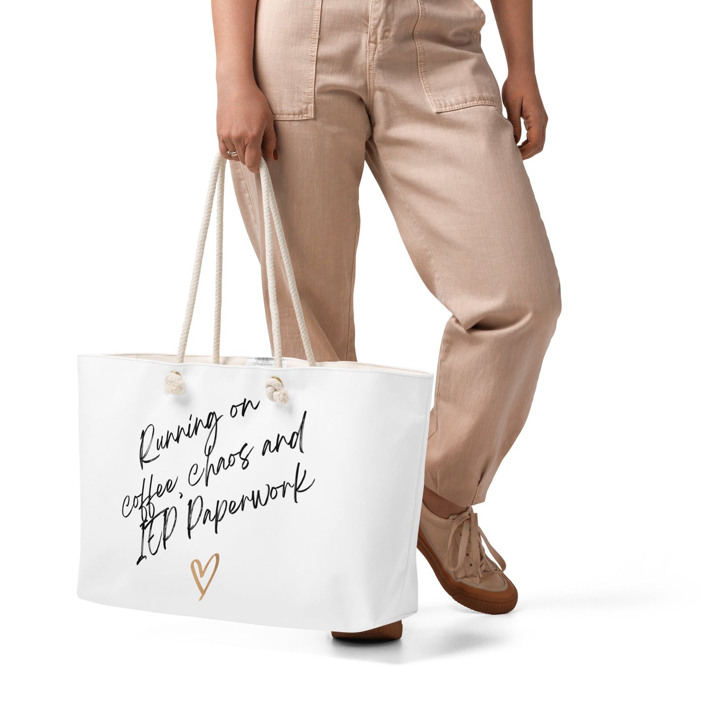 Person holding a white tote bag with text and a heart design on a white background