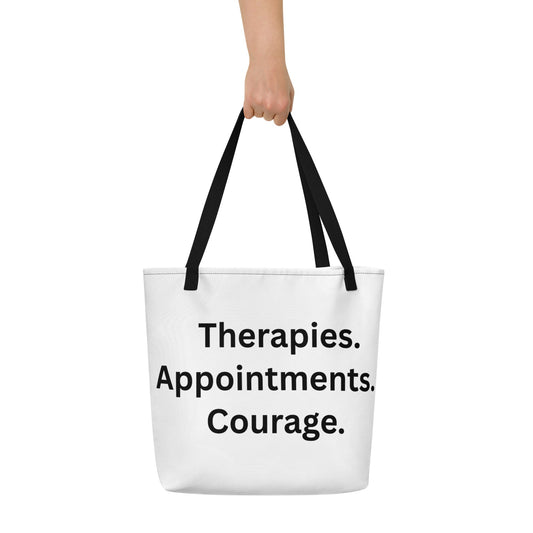 White tote bag with black text 'Therapies. Appointments. Courage.' held by a person on a white background