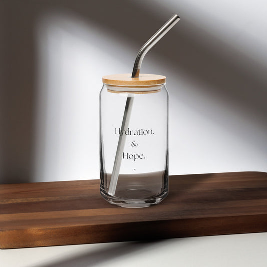 Clear glass jar with wooden lid and straw on a wooden surface
