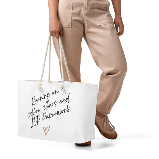 Person holding a white tote bag with text and a heart design on a white background