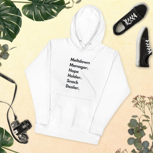 White hoodie with text, black sneakers, camera, and plants on a beige background