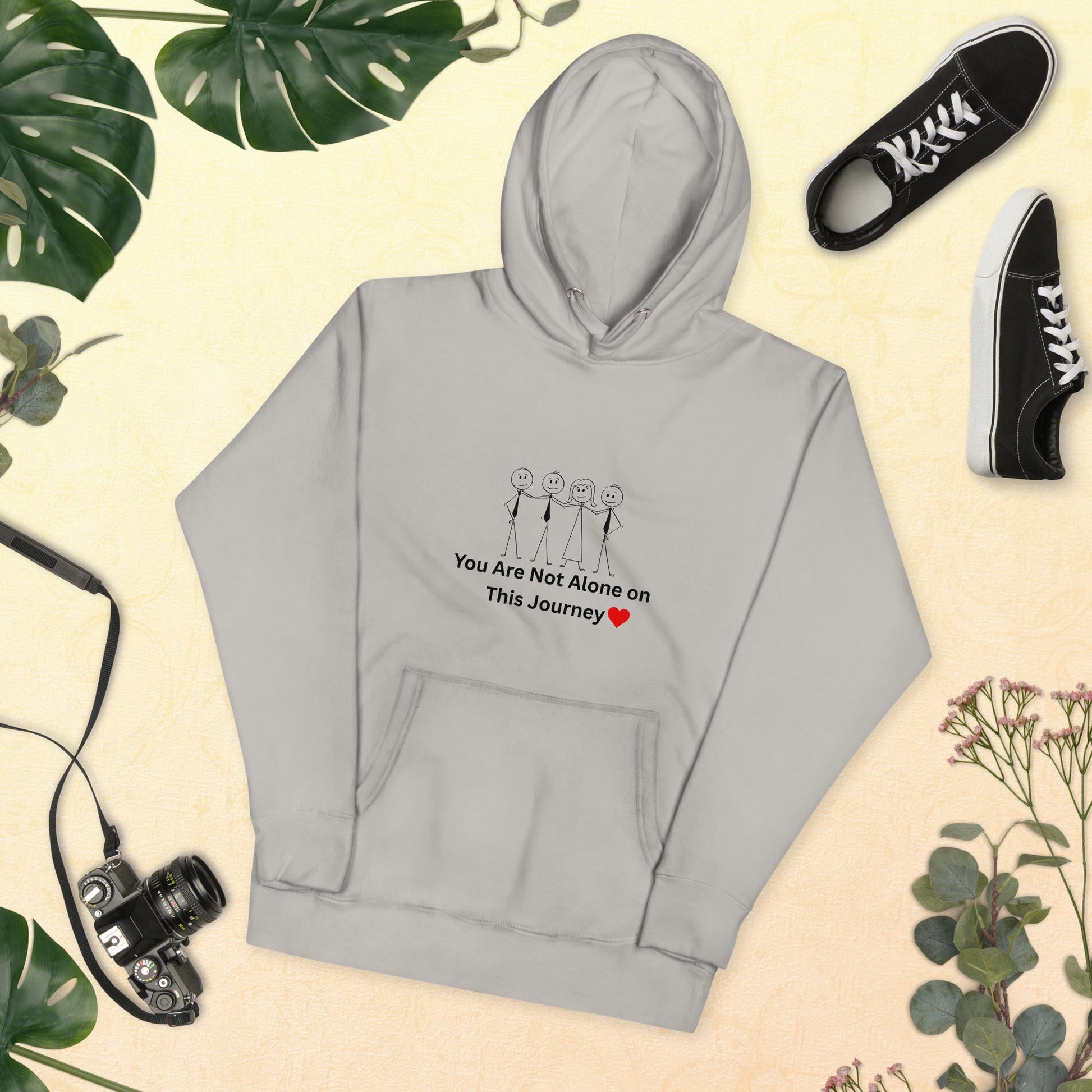 Gray hoodie with motivational text and graphics on a beige background with plants and shoes.